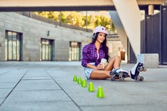 Sportflicka som vilar, når rollerblading av slalom och att ha druckit kaffe arkivbild Sportflicka som vilar, når rollerblading av slalom och att ha druckit kaffe arkivbild