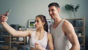 Sportief jong paar die selfie samen thuis het stellen voor smartphonecamera nemen stock video Sportief jong paar die selfie samen thuis het stellen voor smartphonecamera nemen stock video