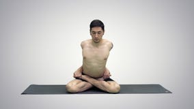 Sportig härlig övande yoga för ung man, sitta som kors-läggas benen på ryggen i Adho Mukha Padmasana som böjer framåtriktat i var arkivbilder Sportig härlig övande yoga för ung man, sitta som kors-läggas benen på ryggen i Adho Mukha Padmasana som böjer framåtriktat i var arkivbilder