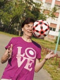 Sporting an old woman enthusiastically tries to catch ball thrown to her.Playing football.