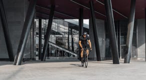 Sportman berijdende fiets naast de moderne bouw binnen stedelijke brug stock foto Sportman berijdende fiets naast de moderne bouw binnen stedelijke brug stock foto