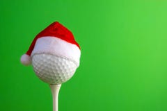 Sports concept on the topic of golf, Christmas and New Year. White golf-ball in a red Santa Claus hat set on a tee. Green