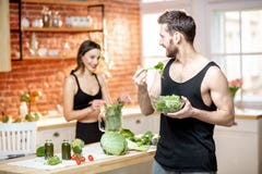 Sports couple eating healthy vegetarian food on the kitchen stock photo Sports couple eating healthy vegetarian food on the kitchen stock photo