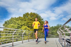 Sporty couple running across a bridge in summer Stock Photo Sporty couple running across a bridge in summer Stock Photo