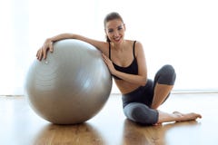 Sporty młoda kobieta pozuje z balową i patrzeje kamerą w domu obraz royalty free Sporty młoda kobieta pozuje z balową i patrzeje kamerą w domu obraz royalty free