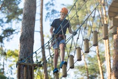 Sporty, young, cute boy in white t shirt spends his time in adventure rope park in helmet and safe equipment in the park royalty free stock images Sporty, young, cute boy in white t shirt spends his time in adventure rope park in helmet and safe equipment in the park royalty free stock images
