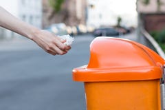 Spreco di lancio nell'una pattumiera arancio nella via Fotografia Stock Libera da Diritti Spreco di lancio nell'una pattumiera arancio nella via Fotografia Stock Libera da Diritti
