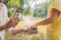 Sprej för farsa- och sonbruksmygga Bespruta krypimpregneringsmedlet på utomhus- hud fotografering för bildbyråer Sprej för farsa- och sonbruksmygga Bespruta krypimpregneringsmedlet på utomhus- hud fotografering för bildbyråer