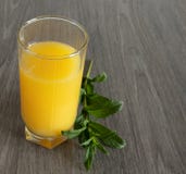 Sprig мяты рядом со стеклом желтого сока на деревянном столе стоковые изображения Sprig мяты рядом со стеклом желтого сока на деревянном столе стоковые изображения