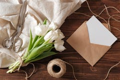 Spring bouquet of white tulip flowers, kraft envelope with blank card, scissors, twine on rustic wooden table. Wedding day composi royalty free stock photos Spring bouquet of white tulip flowers, kraft envelope with blank card, scissors, twine on rustic wooden table. Wedding day composi royalty free stock photos