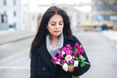 Beautiful young woman with flowers outdoor portrait, spring girl hold fresh bouquet, fashionable elegant lady at city Royalty Free Stock Photos Beautiful young woman with flowers outdoor portrait, spring girl hold fresh bouquet, fashionable elegant lady at city Royalty Free Stock Photos