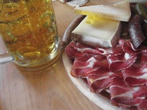 Spuntino tirolese del sud tipico con la macchietta, il formaggio della montagna, le salsiccie affumicate e una tazza fredda di bi fotografia stock Spuntino tirolese del sud tipico con la macchietta, il formaggio della montagna, le salsiccie affumicate e una tazza fredda di bi fotografia stock