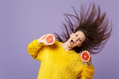Spännande ung kvinna med flödande hår som håller öppna rymmande halfs för mun av den nya mogna grapefrukten som isoleras på viole royaltyfri foto Spännande ung kvinna med flödande hår som håller öppna rymmande halfs för mun av den nya mogna grapefrukten som isoleras på viole royaltyfri foto