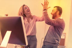Spécialistes gais se donnant de hauts cinq pour montrer l'appui photo stock Spécialistes gais se donnant de hauts cinq pour montrer l'appui photo stock