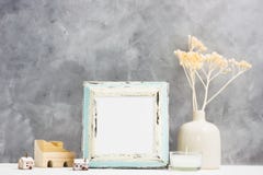 Square blue Photo frame mock up with dry beige plants in vase, wooden houses on shelf. Scandinavian style stock images Square blue Photo frame mock up with dry beige plants in vase, wooden houses on shelf. Scandinavian style stock images
