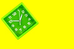 Square green alarm clock on yellow background stock images Square green alarm clock on yellow background stock images