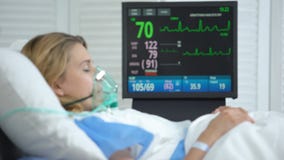 Stabilized woman in oxygen mask sleeping, intensive care hospital unit, surgery
