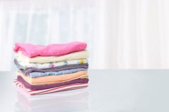 Stack of colorful cute girl clothes. A pile of an colorful clothes on a white table against bright abstract blurred background. stock image Stack of colorful cute girl clothes. A pile of an colorful clothes on a white table against bright abstract blurred background. stock image