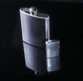Stainless hip flask and lighter isolated on mirror black background. Stock Photos Stainless hip flask and lighter isolated on mirror black background. Stock Photos
