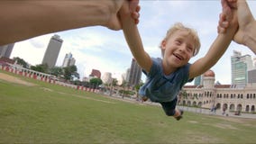Standpunt slowmotion schot van een gelukkige vader die zijn zoon in een park spinnen stock videobeelden Standpunt slowmotion schot van een gelukkige vader die zijn zoon in een park spinnen stock videobeelden