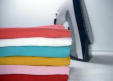 Stapel der gebügelten Kleidung und des Eisens auf weißem Hintergrund lizenzfreie stockbilder Stapel der gebügelten Kleidung und des Eisens auf weißem Hintergrund lizenzfreie stockbilder