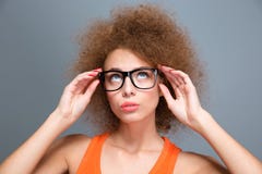 Starke junge gelockte Frau in den schwarzen Gläsern, die oben schauen lizenzfreies stockbild Starke junge gelockte Frau in den schwarzen Gläsern, die oben schauen lizenzfreies stockbild
