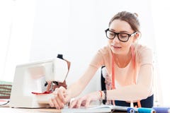Starke tragende Gläser der Frauennäherin, die in der Werkstatt stehen und arbeiten stockbild Starke tragende Gläser der Frauennäherin, die in der Werkstatt stehen und arbeiten stockbild