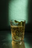 Staromodny szkło z alkoholu napojem i kawałkiem mennica przeciw zieleni ścianie Niski i opatulony światło zdjęcia stock Staromodny szkło z alkoholu napojem i kawałkiem mennica przeciw zieleni ścianie Niski i opatulony światło zdjęcia stock