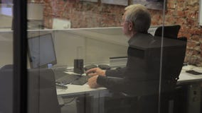 Starszy szef pracuje przy komputerowym obsiadaniem w pomyślnej firmie zbiory wideo Starszy szef pracuje przy komputerowym obsiadaniem w pomyślnej firmie zbiory wideo