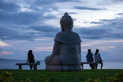 Statua Buddha i trzy twój kobiety ogląda zmierzch nad oceanem spokojnym zdjęcie stock Statua Buddha i trzy twój kobiety ogląda zmierzch nad oceanem spokojnym zdjęcie stock