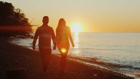 Steadicam сняло: молодые мульти-этнические пары держа руки, идя вдоль seashore на заходе солнца Азиатские человек и кавказец стоковое фото Steadicam сняло: молодые мульти-этнические пары держа руки, идя вдоль seashore на заходе солнца Азиатские человек и кавказец стоковое фото