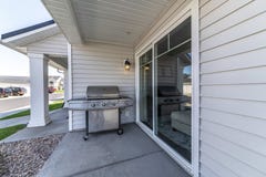 Steel burner gas barbecue grill under the lamp outside the house with vinyl wall siding