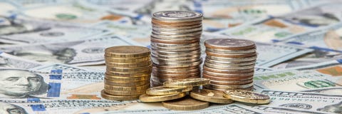 Sterty monety na rozrzuconych notatkach dolary na genialnym tle zdjęcia stock Sterty monety na rozrzuconych notatkach dolary na genialnym tle zdjęcia stock