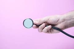 Stethoscope holded in hand in pink purple background stock photos Stethoscope holded in hand in pink purple background stock photos