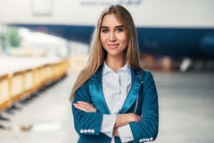 Stewardess i likformig mot flygplatsbyggnad royaltyfri bild Stewardess i likformig mot flygplatsbyggnad royaltyfri bild