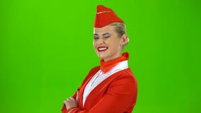 Stewardess in a red suit winks a slight flirt. Green screen. Side view
