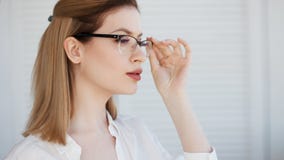 Stilfulla exponeringsglas i en tunn ram, visionkorrigering St?ende av en ung kvinna royaltyfri bild Stilfulla exponeringsglas i en tunn ram, visionkorrigering St?ende av en ung kvinna royaltyfri bild