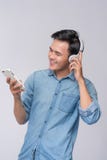 Stilig bärande hörlurar för ung man och innehavmobiltelefon w royaltyfri foto Stilig bärande hörlurar för ung man och innehavmobiltelefon w royaltyfri foto