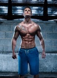 Stilig idrotts- ung man med tatueringen som ser upp arkivfoto Stilig idrotts- ung man med tatueringen som ser upp arkivfoto