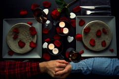 Stiliga unga par som har den romantiska matställen som rymmer händer Top beskådar Stearinljus, blommor och vin arkivfoto Stiliga unga par som har den romantiska matställen som rymmer händer Top beskådar Stearinljus, blommor och vin arkivfoto