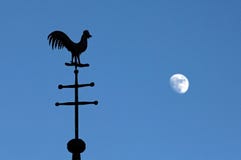 Still life of weathercock and moon in blue sky