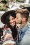 Stilvolle Hippie-Paare, die selfie nehmen und herein am Wasserfall küssen stockbilder Stilvolle Hippie-Paare, die selfie nehmen und herein am Wasserfall küssen stockbilder