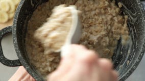 Stirring oatmeal porridge in cooking pan