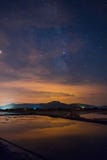 Stjärnklar himmel reflekterade i vattnet med några moln överst av ett berg royaltyfria foton Stjärnklar himmel reflekterade i vattnet med några moln överst av ett berg royaltyfria foton
