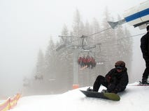 Stoeltjeslift met mensen in mist Snowboarderzitting bij de lift stock foto's Stoeltjeslift met mensen in mist Snowboarderzitting bij de lift stock foto's