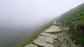 Stone pathway disappearing to vanishing point with drop over edge into fog high up at narrow point on PYG trail on Mount Snowdon i stock images Stone pathway disappearing to vanishing point with drop over edge into fog high up at narrow point on PYG trail on Mount Snowdon i stock images
