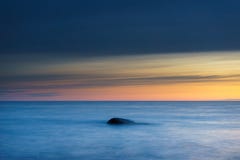 Stone in sea waves against colorful morning sky stock image Stone in sea waves against colorful morning sky stock image