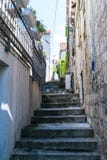 Stone stairs on narrow street among medieval walls in small town of Croatia. Stairs in the city. Old wall and metal fence with stock photography Stone stairs on narrow street among medieval walls in small town of Croatia. Stairs in the city. Old wall and metal fence with stock photography