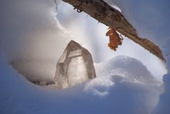 Stor glänsande kristall av genomskinlig kvarts i solljuset på närbilden för snövinterbakgrund arkivbild Stor glänsande kristall av genomskinlig kvarts i solljuset på närbilden för snövinterbakgrund arkivbild