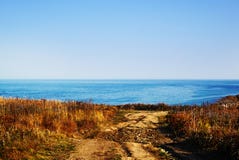 Strada rustica alla spiaggia Il panorama di un mare blu immagine stock Strada rustica alla spiaggia Il panorama di un mare blu immagine stock